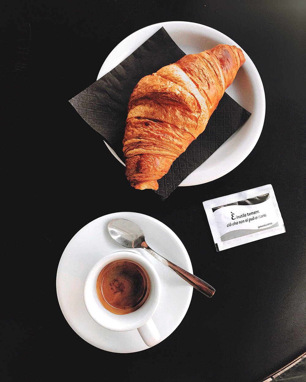 Una taza de café junto a un croissant