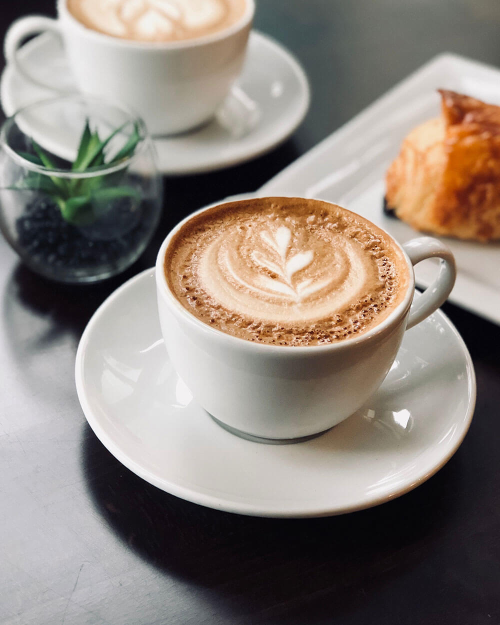 Una taza de café con un diseño bonito de una hoja